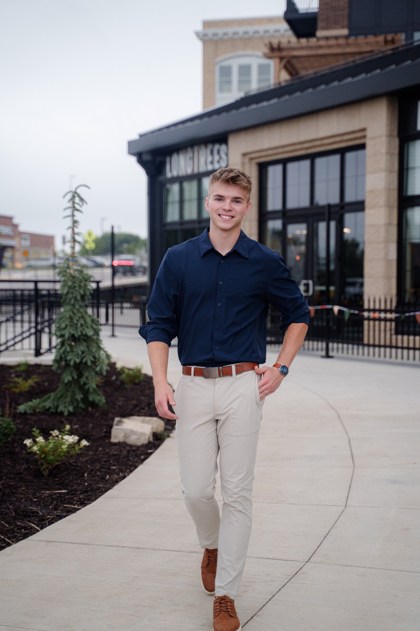 Logan Haburn walking outside in a navy shirt and light trousers